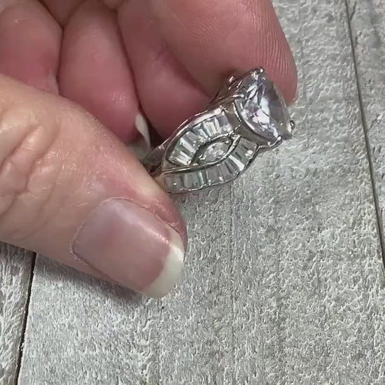 Video of the retro vintage sterling silver CZ heart ring. There is a large heart shaped cubic zirconia stone at the top. There are two curved bands on either side with marquis and trapezoid shaped cubic zirconia. The video shows how much the CZ stones sparkle and all the glitz and glam of the ring.