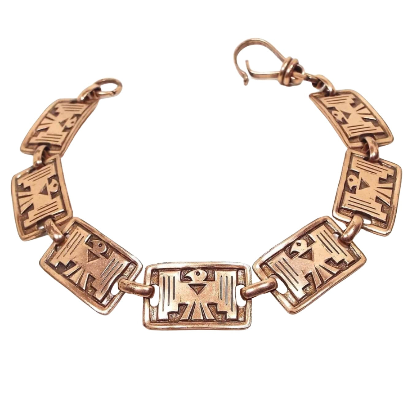 Top view of the retro vintage Sunbell Trading Post panel bracelet. It is copper in color with rectangle links. Each link has a Thunderbird symbol on it. There is a hinged clip clasp at the end.