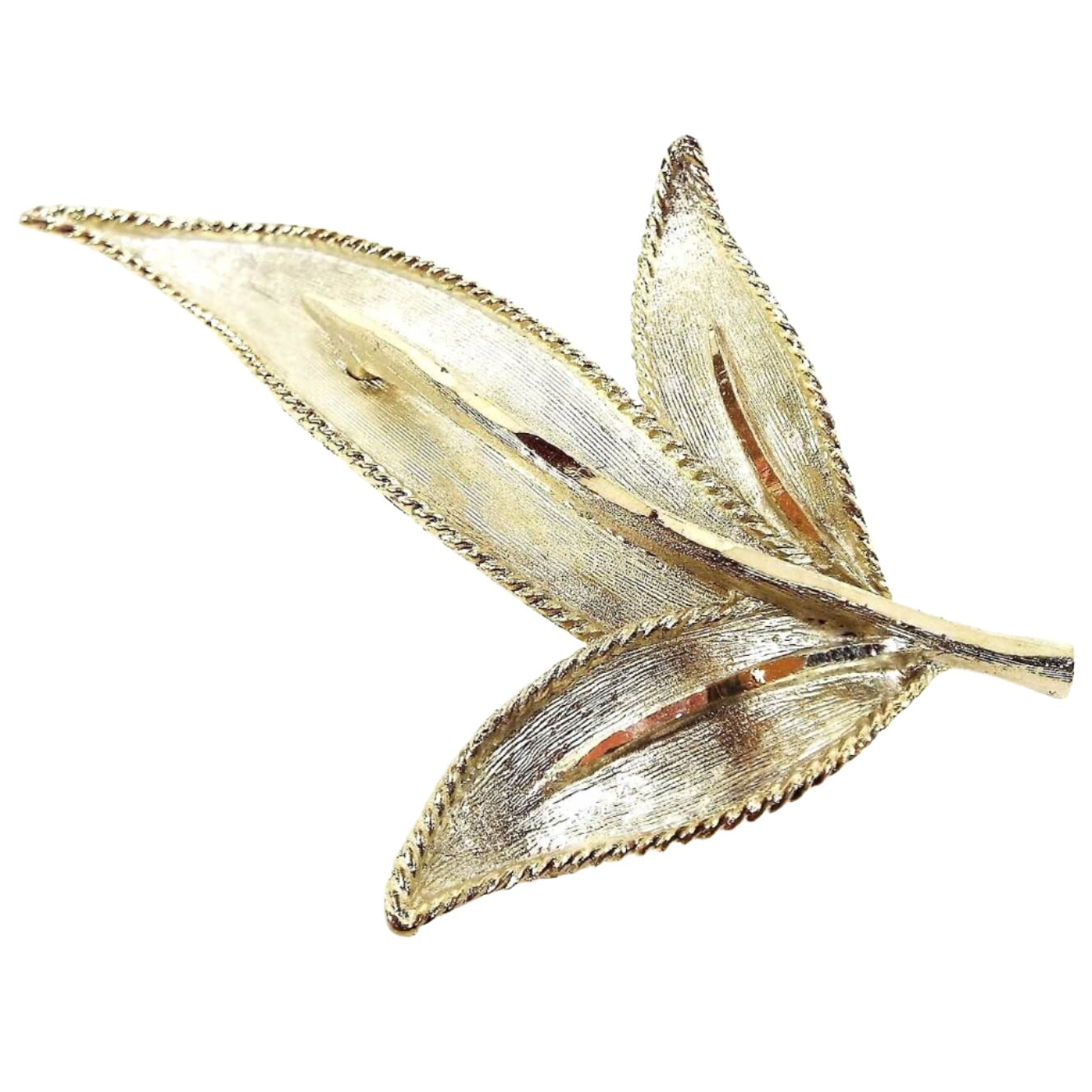 Front view of the retro vintage BSK brooch pin. The metal is textured and a light gold tone in color. It's shaped like a leaf with three leaf areas coming off the stem.