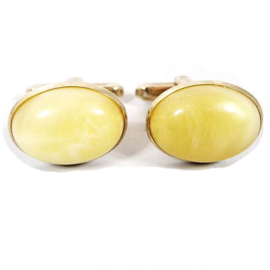 Front view of the Mid Century vintage Hickok lucite cufflinks. They are oval in shape with gold tone color metal. The lucite cabs are domed and a light marbled yellow color.