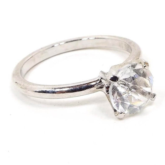 Angled front and side view of the retro vintage Uncas cubic zirconia solitaire ring. The metal is silver tone in color. There is a single round prong set CZ stone at the top.