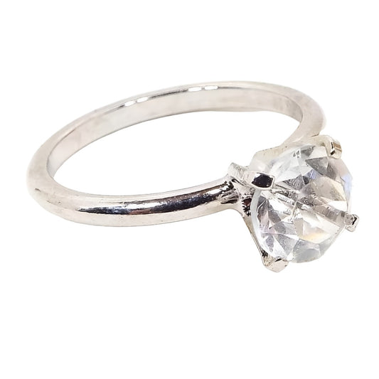 Angled front and side view of the retro vintage Uncas cubic zirconia solitaire ring. The metal is silver tone in color. There is a single round prong set CZ stone at the top.