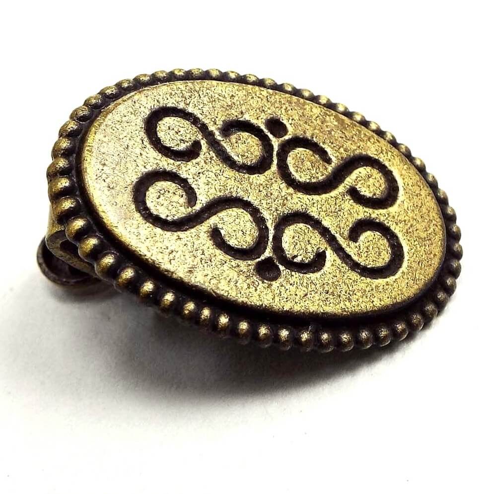 Front view of the retro vintage small oval tie clip. The metal is antiqued brass in color and has an S and dot style design on the front. 