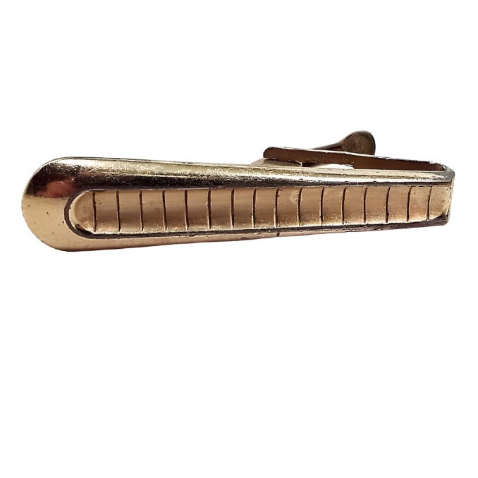 Front view of the Mid Century vintage Foster tie clip. The metal is gold tone in color. it flares out to a rounded end and has line stripes etched down the length of it.