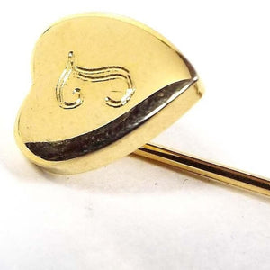 Enlarged view of the Mid Century vintage initial stick pin. The metal is gold tone in color.  There is a heart shape at the top with a fancy letter T engraved on it.