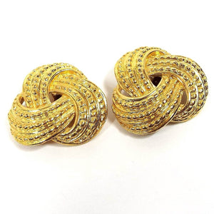 Front view of the retro vintage shoe clips. The metal is gold tone plated in color. They are shaped like twisted knots and have a bumpy textured pattern on them.