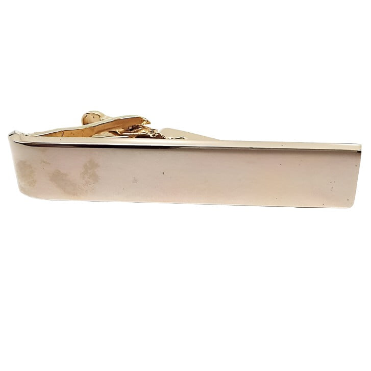 Front view of the retro vintage tie clip. The metal is gold tone in color. It is a basic plain smooth rectangle style design.