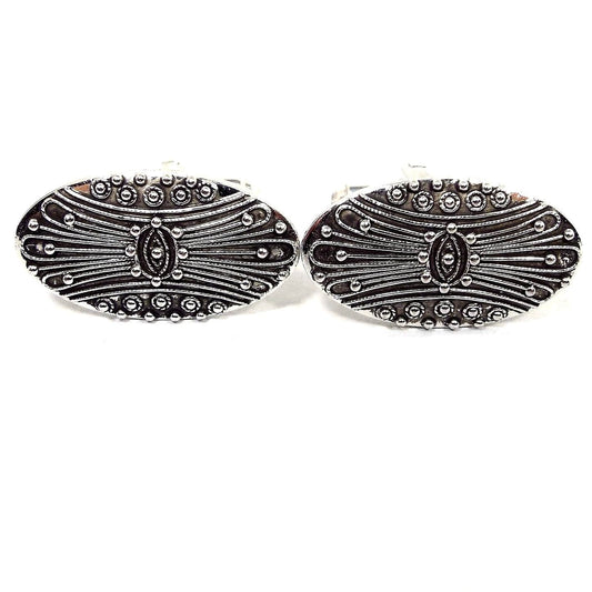 Front view of the Mid Century vintage Shields cufflinks. They are oval in shape and have an antiqued silver tone color on the front. There is a raised curvy line and dot pattern.