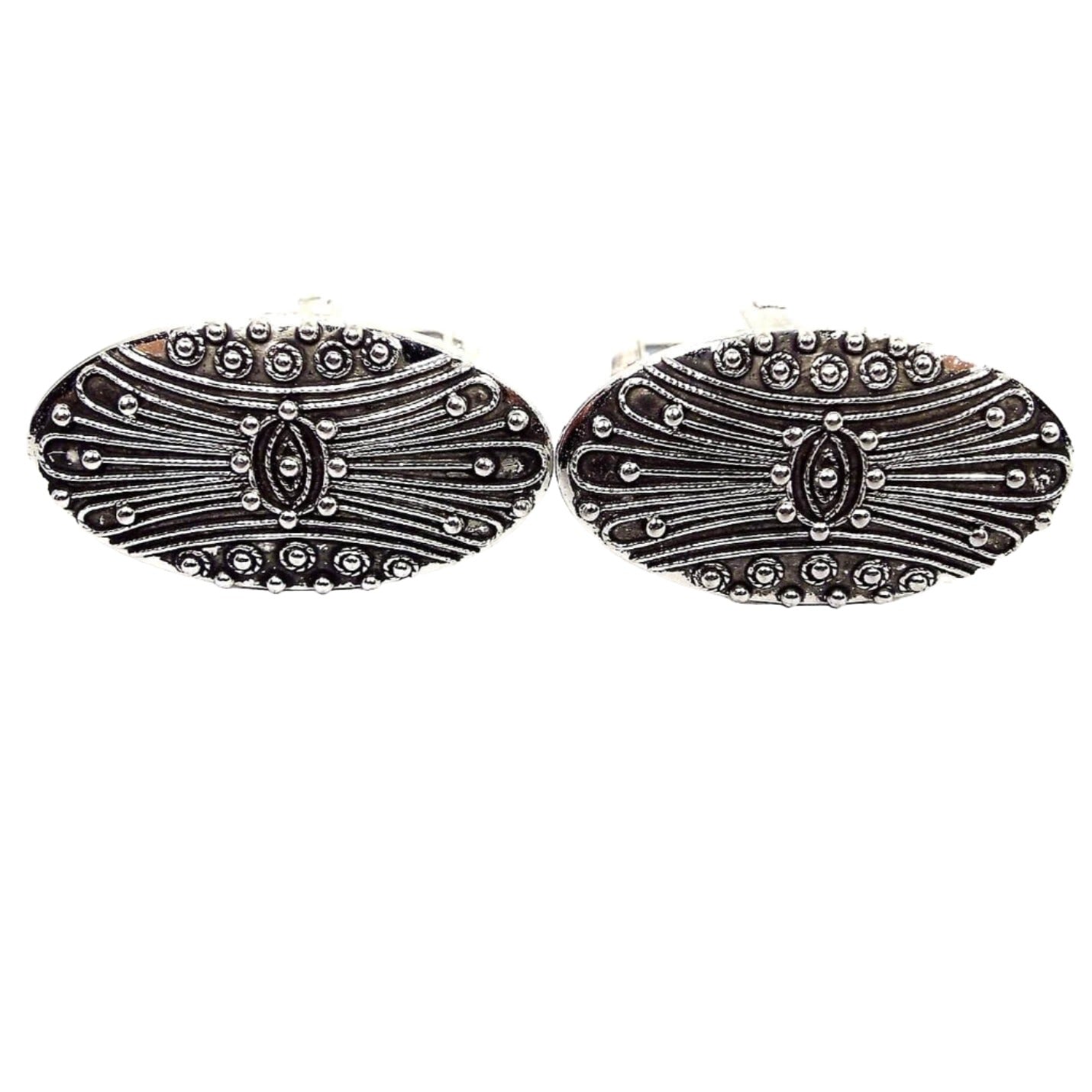 Front view of the Mid Century vintage Shields cufflinks. They are oval in shape and have an antiqued silver tone color on the front. There is a raised curvy line and dot pattern.