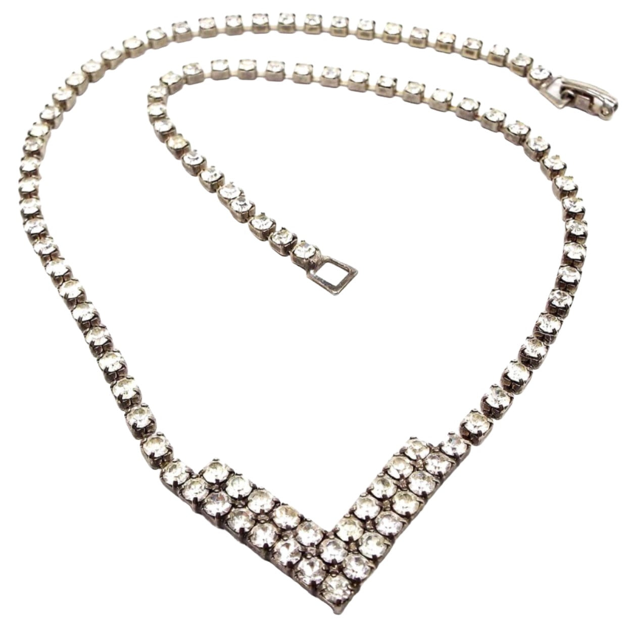 Front view of the retro vintage rhinestone necklace. The metal is a darkened silver tone in color. There is a round of small round rhinestones down to a double row V shape at the bottom. There is a snap lock clasp on the end. 