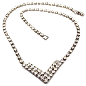 Front view of the retro vintage rhinestone necklace. The metal is a darkened silver tone in color. There is a round of small round rhinestones down to a double row V shape at the bottom. There is a snap lock clasp on the end. 