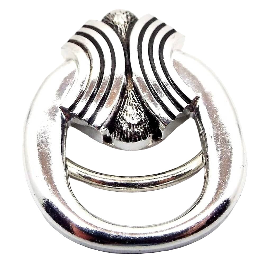 Front view of the Mid Century vintage scarf clip from Western Germany. It is metallic silver tone in color. There is a large rounded oval with a textured part on top. The top has bands curving outwards.