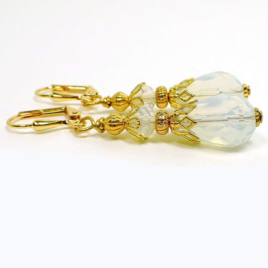 Side view of the handmade faceted glass crystal teardrop earrings. The metal is gold plated in color. The beads are translucent with a slightly cloudy opal color appearance.