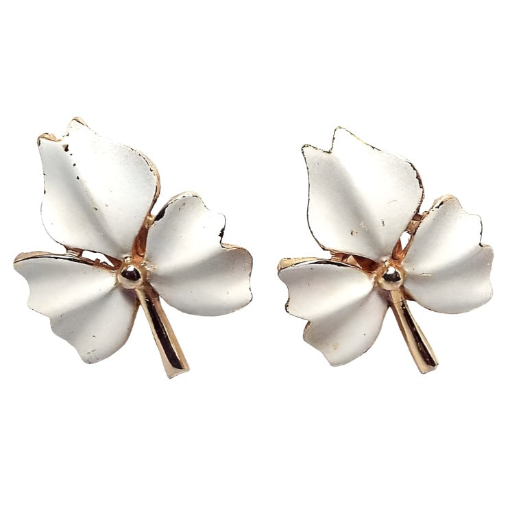 Front view of the 1960's Mid Century vintage clip on leaf earrings. The metal is gold tone in color. The earrings are shaped like leaves with three parts to them. The front of each part is white enameled. 