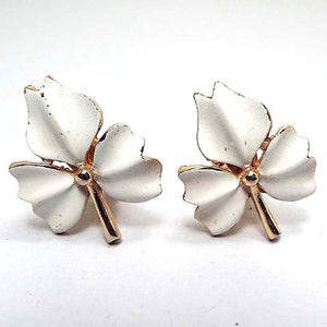 Front view of the 1960's Mid Century vintage clip on leaf earrings. The metal is gold tone in color. The earrings are shaped like leaves with three parts to them. The front of each part is white enameled. 