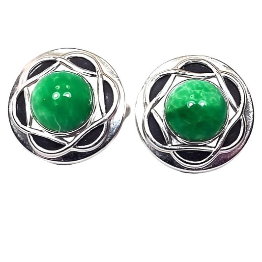 Front view of the Mid Century vintage Anson cufflinks. They are round and silver in color. In the middle of each one is a rounded fancy glass cab that is marbled with shades of green and a little bit of white. Around the glass cabs is a woven Celtic style design. 