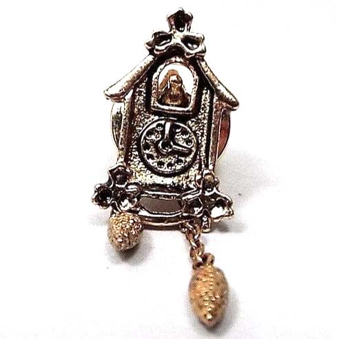 Front view of the retro 1980's Avon cuckoo clock tie tack. It's made of metal and is darkened gold tone in color. The top part is open showing the bird and there are two danging metal beads on chain to resemble the clock weights. The clock hands don't move and it looks like it's showing as 3 o clock.