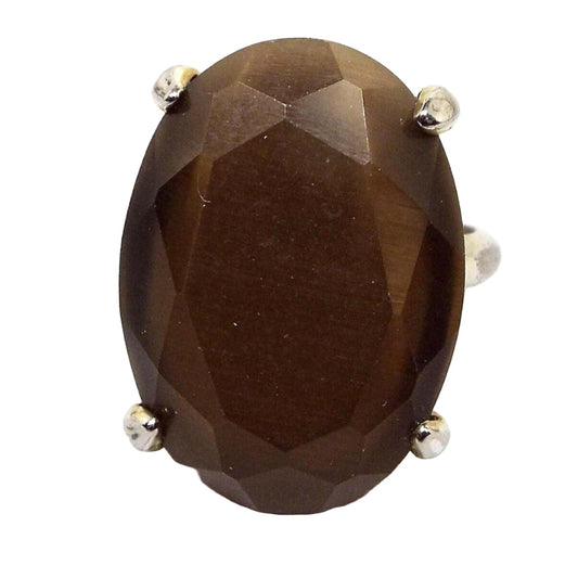 Top view of the retro vintage faux cat's eye statement ring. It has a prong set maximalist style large oval faceted glass stone that has some flash as you move around. The metal is gold tone in color.