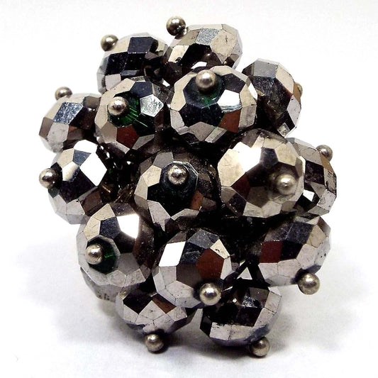 Top view of the retro vintage cluster beaded adjustable ring. The beads are faceted rondelles that are metallic gray for a faux hematite look. There are tiny silver tone round beads at the end of each one. The beads form a large cluster on top. 