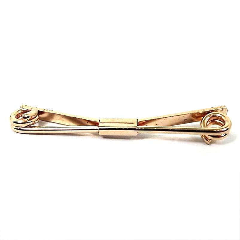 Front view of the Anson Mid Century vintage collar clip. It is gold tone in color. The front has a thick wire bar thas is spiral at the ends. the back is a flat wider bar that is angled. there is a rectangle holding both bars together in the middle.