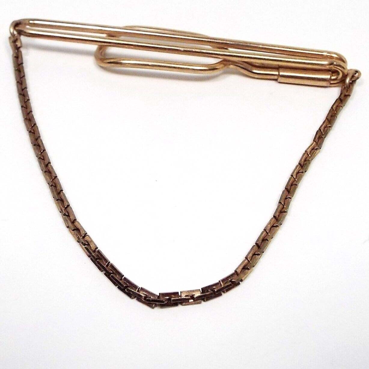 Front view of the 1940's dapper vintage rolled gold plate Swank tie bar chain. The metal is darkened gold tone in color. There is a long open oval wire bar at the top that curves around to the back with another open oval area at the end. The square link chain hangs from each side at the top. 