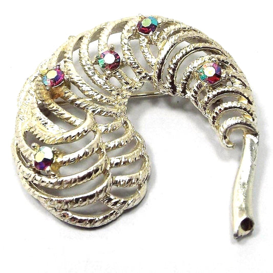 Brooch is gold in color. It has a stem on the right and a curved feather like design on the left. The feather design has cut out filigree areas and 5 randomly placed rhinestones that are AB red in color. The aurora borealis red is a reddish pink in color with flashes of other colors as you move around.