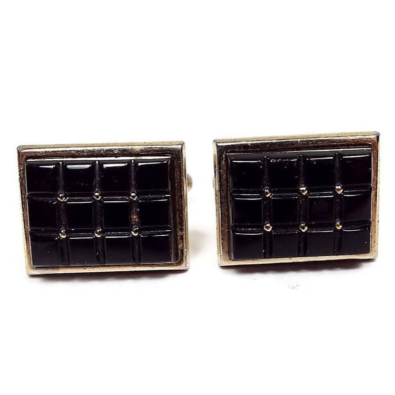 Front view of the Mid Century vintage Anson cufflinks. They are gold tone rectangles with small square black glass cabs in a waffle pattern design.