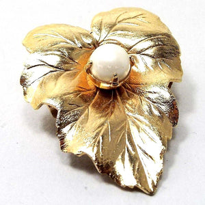 Front view of the Mid Century vintage Sarah Coventry leaf brooch. It is gold tone in color and has a faux pearl in the middle.