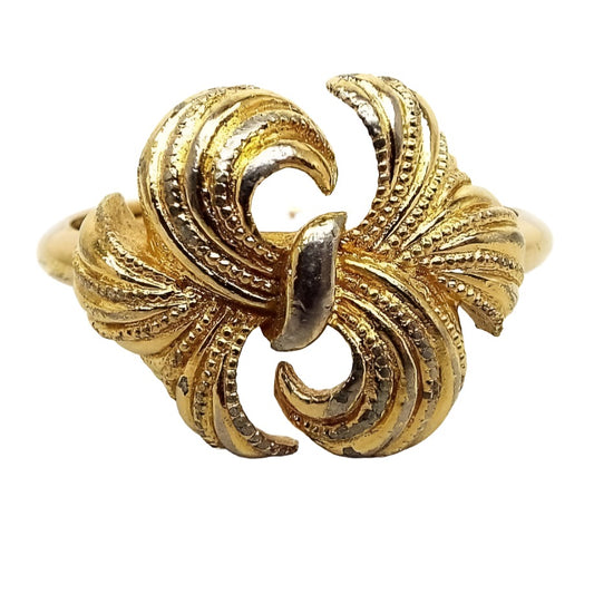 Top view of the retro 1970's Avon vintage bow ring. The metal is gold tone in color. The top has a bow design with textured curved ribbon style flares from the middle. 