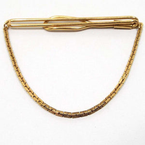 Front view of the 1940's Mid Century vintage Swank tie chain bar. It is gold tone in color. The top has a long open oval wire bar that curves around to the back with a larger open oval area on the end. Square link chain comes down from either side to hang in a curve at the bottom. 