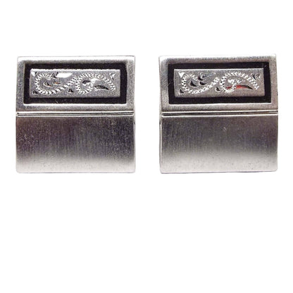 Front view of the Mid Century vintage Speidel cufflinks. They are matte silver tone in color and square shaped. there is a line through the middle of the cufflinks. On the top of the cufflinks is a black painted rectangle with an etched paisley design on the inside.