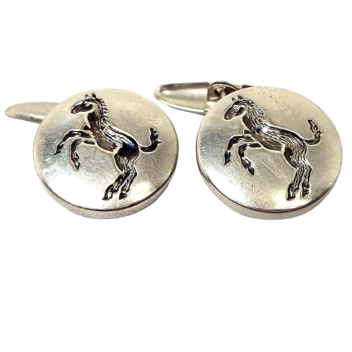 Front view of the Mid Century vintage button style cufflinks. They are round and silver tone in color. There is a side view of a pony or horse stamped in the middle that's painted gray on the inside. Part of the oval link backs are showing on the end of the links.