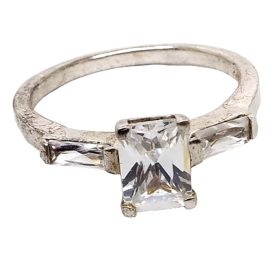Front view of the retro vintage sterling silver cubic zirconia ring. The sterling has some darkened areas from age. There is a rectangle shaped prong set CZ stone in the middle with a baguette CZ stone channel set on each side. 
