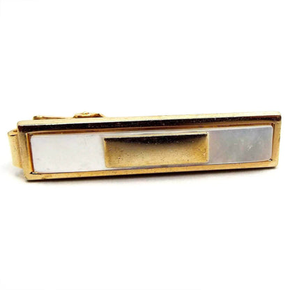 Front view of the Mid Century Anson tie clip. It has a rectangle design. It is gold tone in color with an inlaid rectangle of mother of pearl shell. The shell cab is pearly white in color. Inside the mother of pearl cab is another gold tone color metal rectangle. There is an alligator style clip on the back.