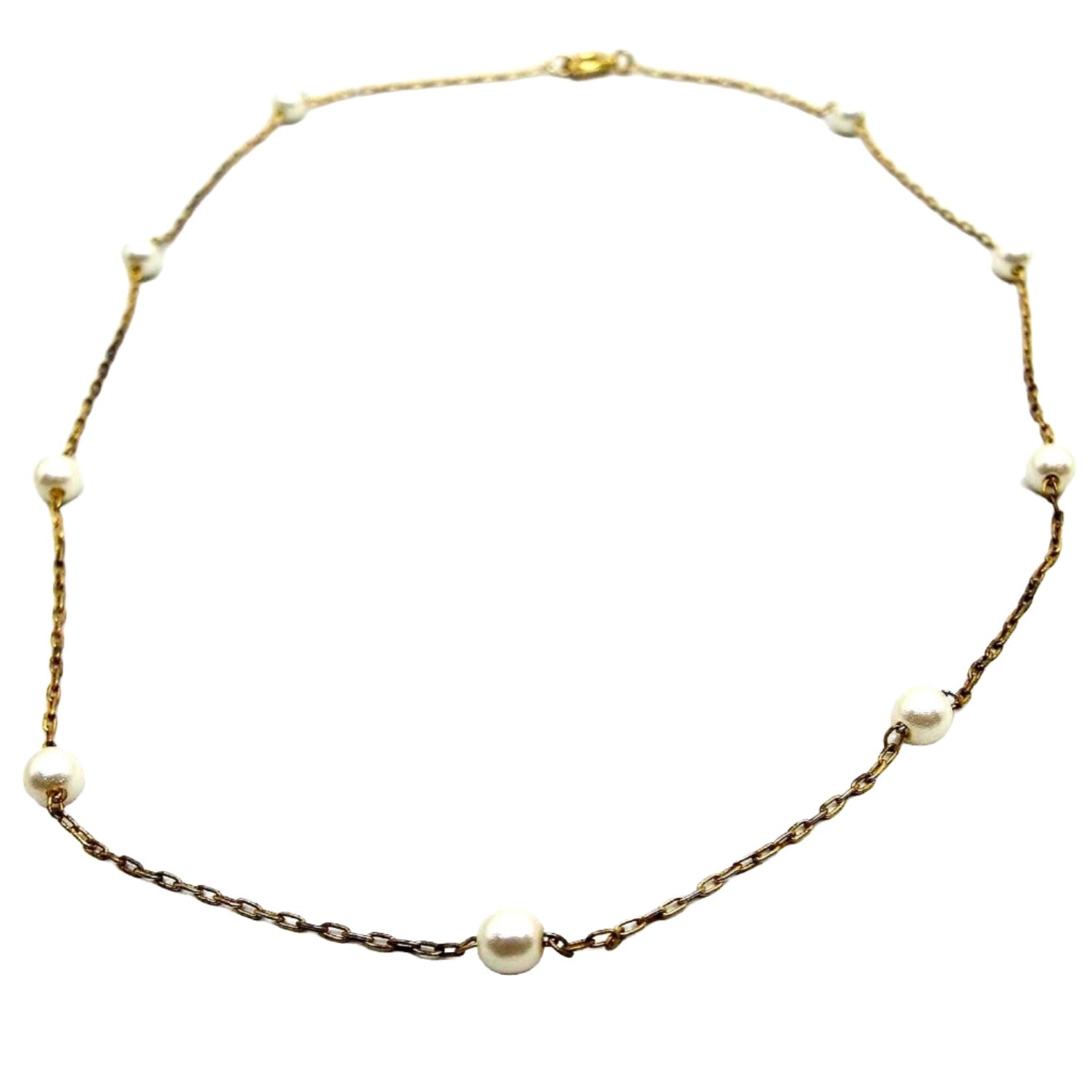 Front view of the retro vintage faux pearl beaded chain necklace. The chain is thin oval cable link and gold tone in color. There is a spring ring clasp at the end. There are nine small round off white glass imitation pearls spread out along the chain.