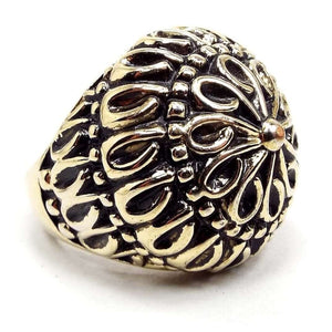 Angled front and side view of the retro vintage dome ring. The plated metal is an antiqued gold tone color with shiny gold color on top of darkened gray areas. The top is rounded with a floral mandala like design. Each petal has a teardrop shaped end. Then there is a row of dots around it, then another row of tear drops and so on until it reaches the bottom band part which is smooth metal. 