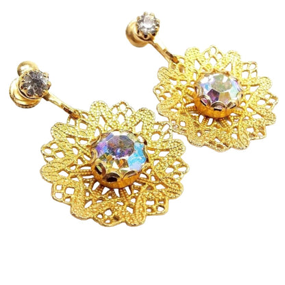 Screw back earrings are gold in color. They have a clear round rhinestones at the top. The bottom drops are large filigree doily style design with a large AB round rhinestone in the middle. The AB rhinestones have light flashes of different colors as you move around. 