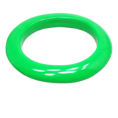 Angled front and side view of the Mid Century vintage lucite bracelet. It's bright green in color and oval shaped. It's fairly wide and thick.