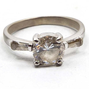 Front view of the retro vintage sterling silver cubic zirconia ring. The sterling is a very slightly darkened silver color. There is  a round prong set CZ stone in the middle with a trapezoid channel set CZ stone on either side.