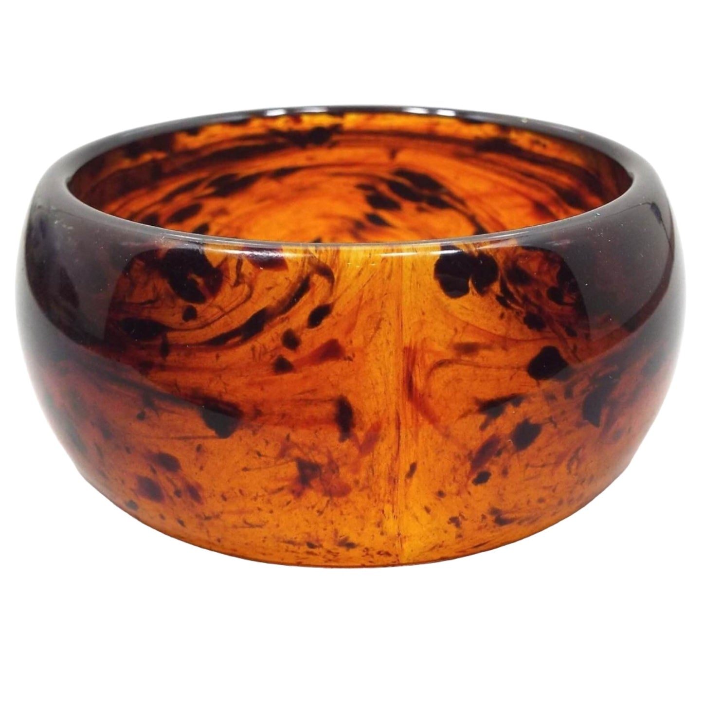 Angled front and side view of the retro vintage lucite plastic bangle bracelet. It is a very wide bangle with curved outer edge. The lucite is semi translucent with areas of orange, brown, and black.