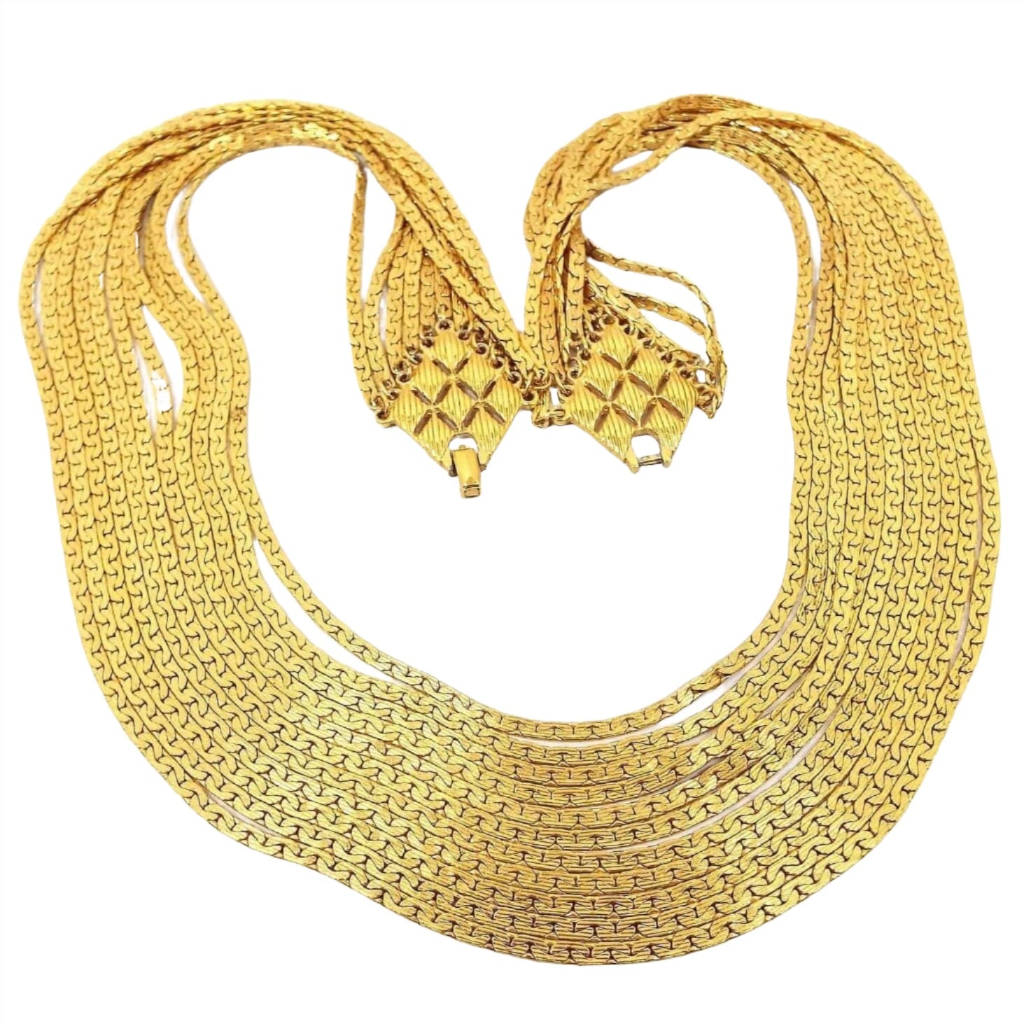 Front view of the Mid Century vintage D'Orlan multi strand chain necklace. There are 11 strands of C link chain in graduating lengths. The chain is flat and has 2 rows of interlocking curve links on each side of the chain. The ends of the necklace attach with small jump rings to an area that has a large diamond pattern. The diamond pattern has 8 smaller diamond shapes inside it that is textured with lines. At the end of each diamond pattern is part of the snap lock clasp. 