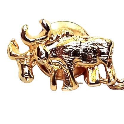Front view of the Mid Century vintage moose tie tack. The metal is gold tone in color. The front has a textured semi 3D side view of two moose standing side by side. the one in the back has his head down some. Both have antlers. The rounded clutch on the back has a curb chain going to a small bar at the end.