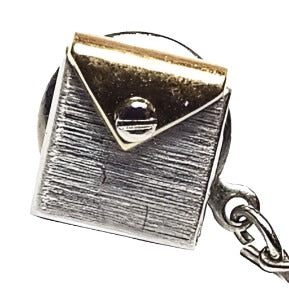 Front view of the retro vintage two tone tie tack. It is square in shape and made to look like an envelope with a gold tone triangular flap and what looks like a small screw head on the top part of the tie tack. The flap is gold tone in color and the rest of the tie tack is brushed matte silver tone in color. The clutch on the back has a chain with a small bar on the end.