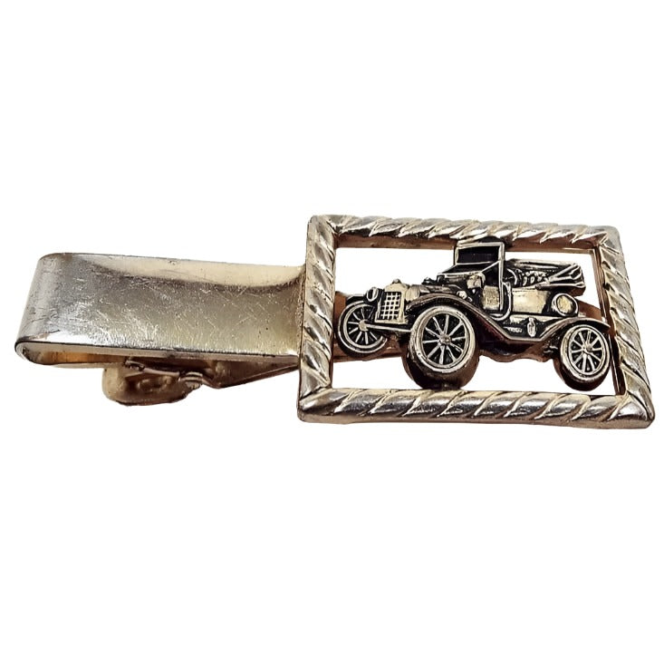 Front view of the Anson antique car vintage tie clip. It is darker gold plated in color with a rectangle on the right side. The rectangle has a diagonal twisted design and has a cut out detailed design of an old automobile. 