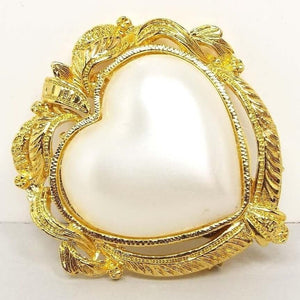 Front view of the retro vintage faux pearl scarf clip. It is shaped like a large puffy heart with a coated plastic imitation pearl heart cab in the middle. The edge has a fancy old style frame like design in gold tone color metal. 