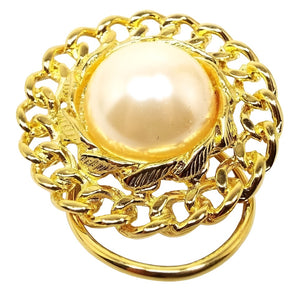 Front view of the retro vintage faux pearl scarf clip. The imitation pearl is a domed round coated plastic cab and has a curb chain like design all the way around the edge. The metal is gold tone in color.