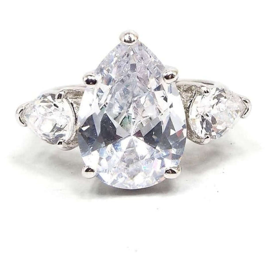 Top view of the retro vintage rhinestone cocktail ring. There is a large sized pear shaped rhinestone at the top with smaller pear shaped rhinestones on each side with their smaller ends pointing downwards. The metal band and setting is silver tone in color. All rhinestones are prong set.