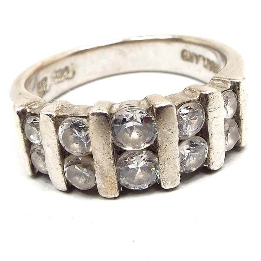 Angled front view of the retro vintage sterling silver cubic zirconia band ring. It has two rows of CZ stones curved across the top. The stones in the middle are the largest in size. All around round and channel set with sterling bars between each set of two. 925 and Thailand can be read on the inside of the band.