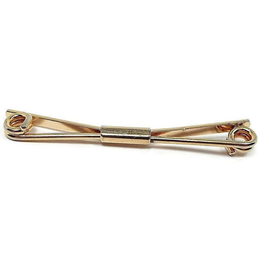 Front view of the Anson Mid Century 1960's vintage collar clip bar. It is gold tone plated in color. The front has a thick wire bar thas is spiraled inward at the ends. the back is a flat wider bar that is angled. there is a rectangle holding both bars together in the middle.