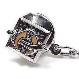Front view of the Anson Mid Century vintage tie tack. The front part of the tie tack is a small square made of sterling silver that has a textured matte surface. On that is the Scimitar and Horn emblem design for the Shriners. The horn part of the design is yellow enameled. The back clutch is shiny silver plated with a chain that has a bar on the end.